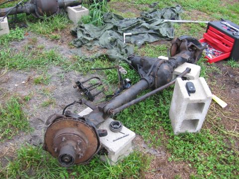 1995 Ford F-150 - Front axle assembly, likely from a truck, is disassembled and resting on concrete blocks outdoors.