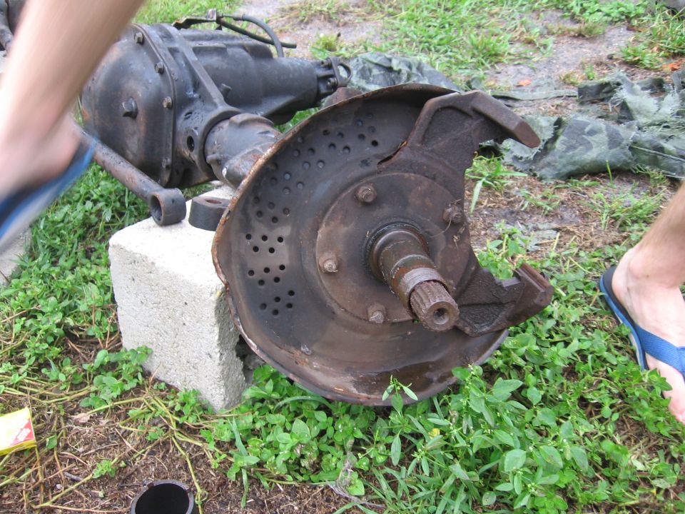 Front axle differential and hub assembly sitting on grass and a cinder block