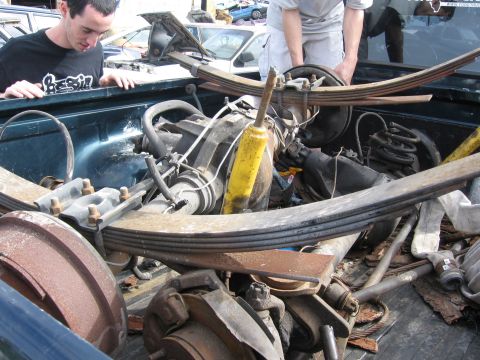 1995 Ford F-150 - Close-up view of a disassembled rear axle assembly, including leaf springs and a yellow shock absorber, in a vehicle bed.