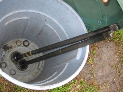 1995 Ford F-150 - Axle shafts are shown inside a large plastic bin, with some bearing races scattered around.