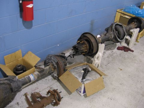 1995 Ford F-150 - Several vehicle rear axle assemblies are laid out on the floor, some in boxes, with a fire extinguisher mounted on the wall.