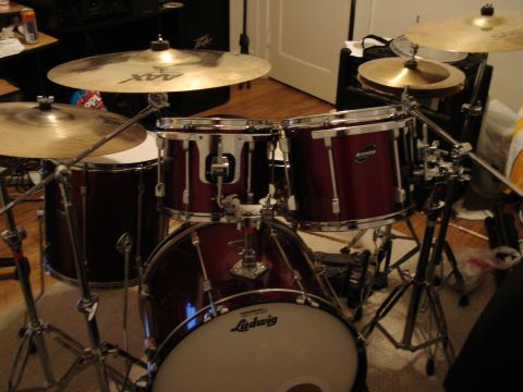 1986 Ford Bronco - A red drum kit is set up indoors, cymbals, toms, and a Ludwig bass drum.