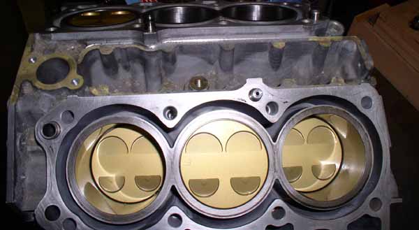 Engine cylinder head showing three pistons inside cylinders