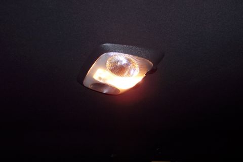 2001 Ford Crown Victoria - The interior dome light of a vehicle is illuminated against the dark headliner.