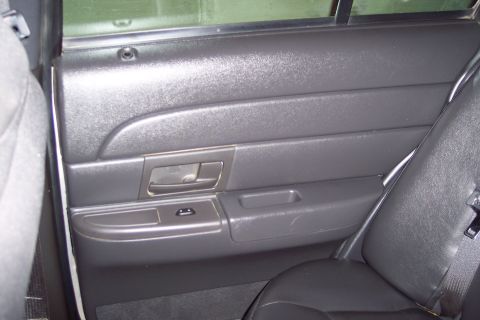 2001 Ford Crown Victoria - Interior view of a car's rear passenger door panel, showing the armrest and window controls.