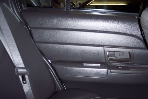 2001 Ford Crown Victoria - Interior view of a black rear passenger door panel with a seatbelt visible.