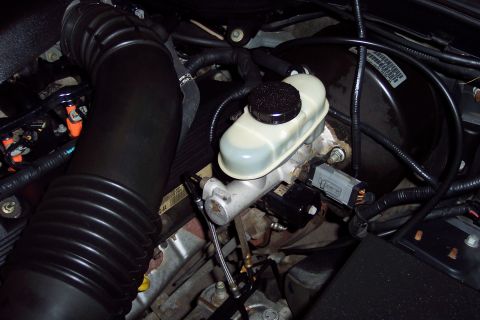 2001 Ford Crown Victoria - Close-up view of the engine bay, focusing on the brake master cylinder and a large ribbed air intake hose.