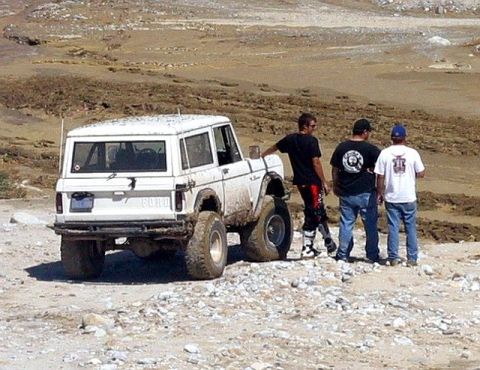 1990 Ford Bronco - White 1990 Ford Bronco in a dry, off-road environment with three men observing.