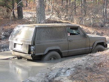 1989 Jeep Cherokee - Muddy 1989 Jeep Cherokee stuck in a water-filled ditch during off-road activity.