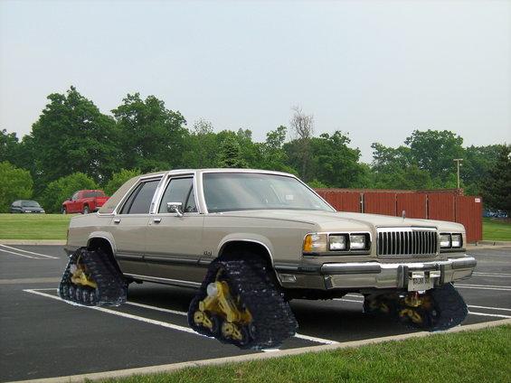Sedan with tank treads instead of wheels, parked in a lot