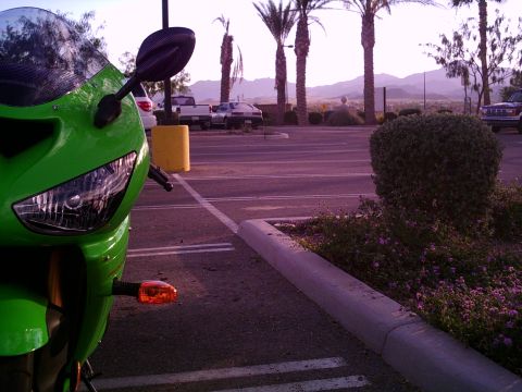 2005 Kawasaki Ninja R - A bright green motorcycle is parked in a lot with palm trees and mountains in the background.