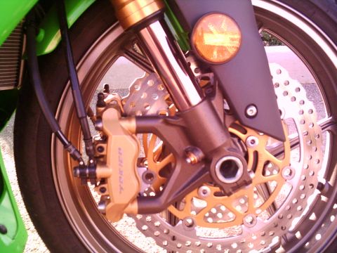 2005 Kawasaki Ninja R - Close-up of a motorcycle's front wheel, showing the brake system and part of the green bodywork.