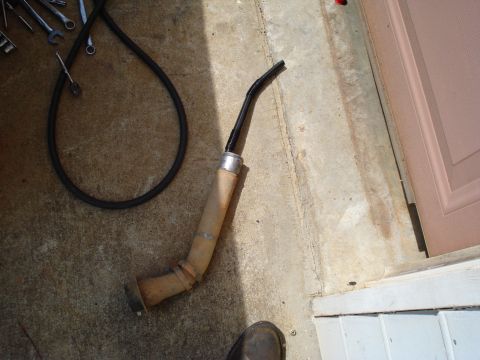 1984 Ford Bronco - Exhaust pipe and hose lying on concrete floor next to a doorway.