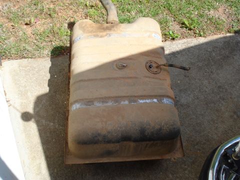 1984 Ford Bronco - A weathered fuel tank rests on a concrete surface, showing signs of age and use.