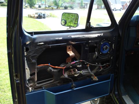 1984 Ford Bronco - Car door interior with exposed wiring and speaker, panel removed for access.