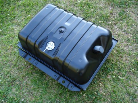 1984 Ford Bronco - A black fuel tank with a metal mounting bracket is shown from an elevated angle on a grassy surface.
