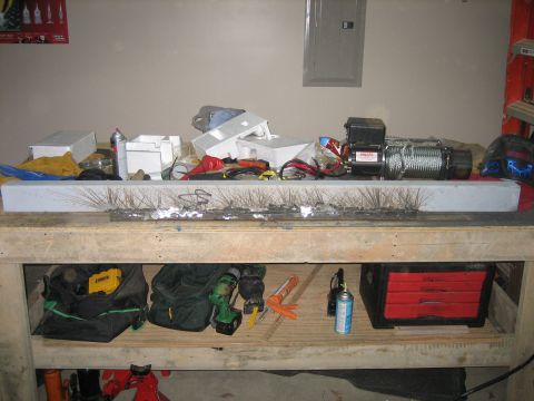 1996 Ford Bronco - Garage workbench with a long welded steel bumper or crossmember section lying across the front, its fresh weld beads still surrounded by gr…
