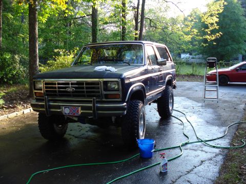 1984 Ford Bronco - Ford Bronco parked in driveway with cleaning supplies and a red car nearby.