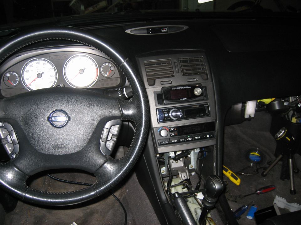 Nissan Maxima dash with aftermarket stereo, lower console panels removed exposing wiring and shifter