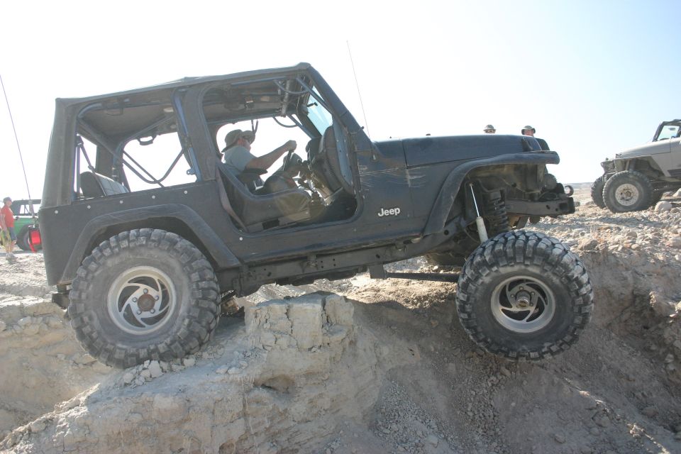 Black Jeep TJ climbing over rocks, another Jeep visible in background