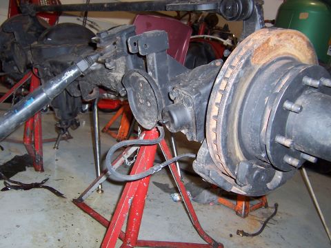 1990 Ford Bronco - A front axle assembly, likely from a truck or SUV, is shown on jack stands, highlighting the brake system components.