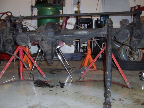 1990 Ford Bronco - Front axle assembly, likely a Dana 60, is supported by jack stands in a workshop setting.