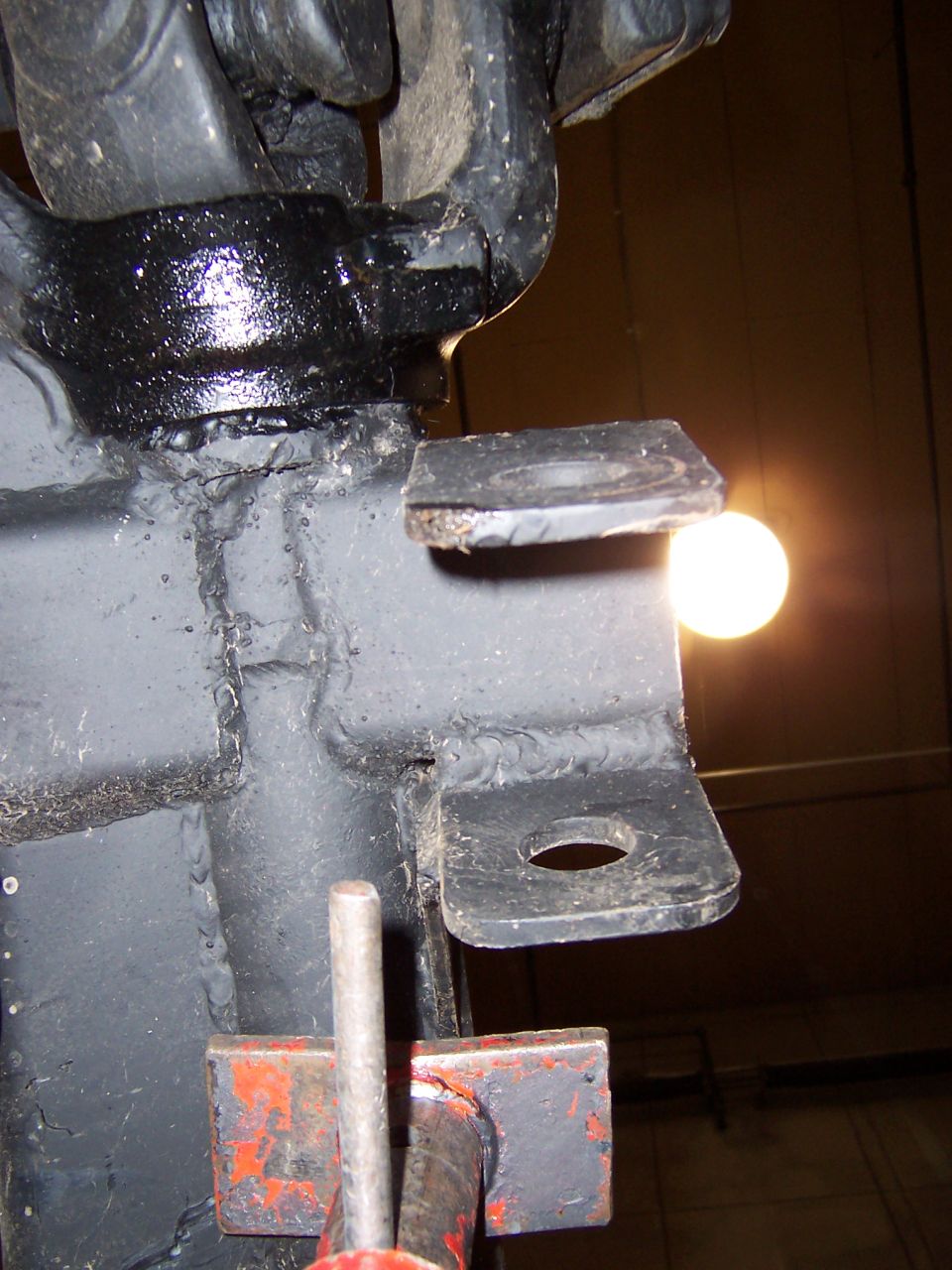 Black metal suspension bracket with a hole, bolted to a larger component