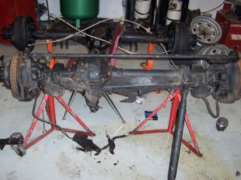 1990 Ford Bronco - Dana 60 front axle assembly and another axle assembly are supported by jack stands in a garage.