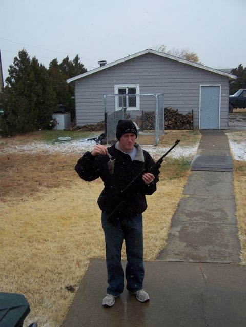 1995 Ford Bronco - A man stands in a snowy yard, holding a small rodent and a rifle.