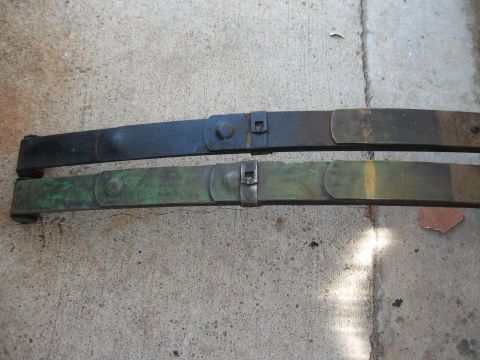 1968 Shelby GT500 - Two leaf springs, likely for a vehicle's suspension, are shown resting on a concrete surface.