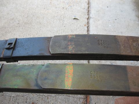 1968 Shelby GT500 - Close-up of two leaf springs, one dark and one with green and orange markings, showing stamped part numbers.