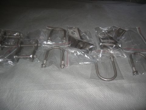 1968 Shelby GT500 - Various metal automotive parts, including brackets and U-bolts, are displayed in individual plastic packaging.