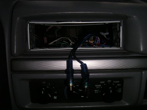 1994 Ford Bronco - The interior of a car shows an empty radio slot with exposed wiring and climate controls below.