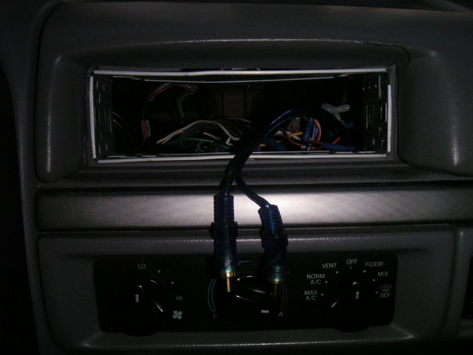 Car interior showing an empty radio slot with wires, climate control knobs, and a SuperMotors watermark