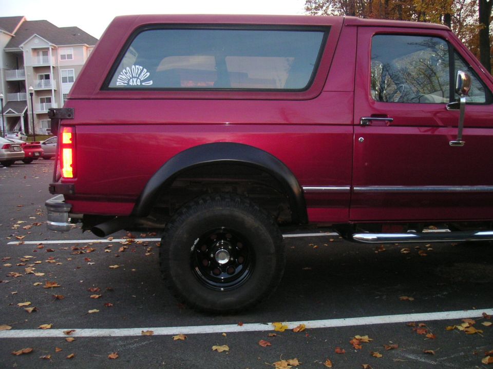 Red 1994 Ford Bronco side view with black fender flares and aftermarket wheels
