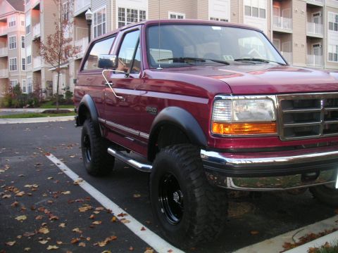 1994 Ford Bronco - A maroon 1994 Ford Bronco is parked in a lot with fallen leaves on the ground.