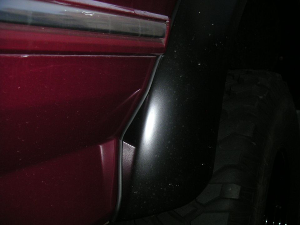 Close-up of a black fender flare and tire next to a dark red body panel