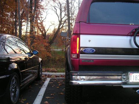 1994 Ford Bronco - Rear view of a 1994 Ford Bronco parked next to a black car in an autumn setting.