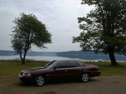 2004 Ford Crown Victoria - Maroon 2004 Ford Crown Victoria parked beside a calm lake on an overcast day.