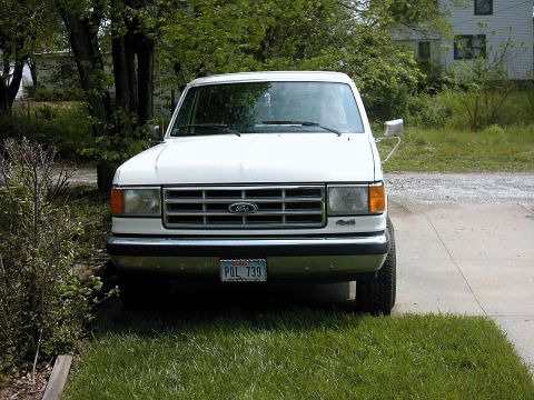 1987 Ford Bronco - Front view of a white 1987 Ford Bronco parked outside on a sunny day.