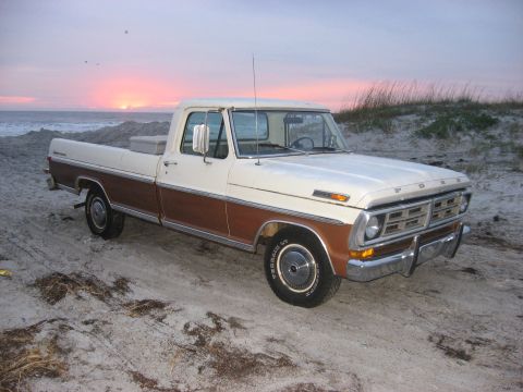 1972 Ford F-100 - This two-tone 1972 Ford F-100 pickup truck with woodgrain trim is seen on a sandy beach during a sunset.