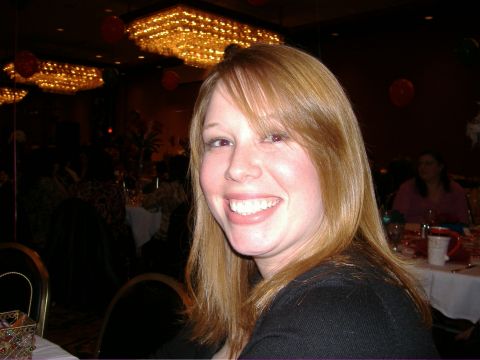 1995 Ford Bronco - A woman smiles broadly while seated at a table in a banquet hall, with decorative chandeliers visible in the background.