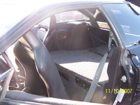 1995 Ford Probe - Interior view of a 1995 Ford Probe, racing seats and a custom speaker setup in the cargo area.