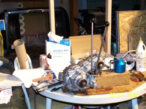1988 Suzuki Samurai - Transfer case with dual shifters on a workbench, with various tools and supplies nearby.