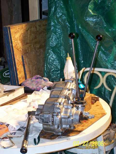 1988 Suzuki Samurai - A transfer case with twin stick shifters sits on a table, surrounded by tools and parts.