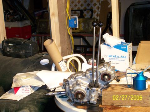 1988 Suzuki Samurai - A transfer case with dual shifters sits on a table, surrounded by various workshop items.