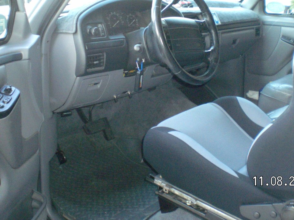 Gray interior of a Ford Bronco showing dash, steering wheel with keys in ignition, and two-tone cloth driver's seat