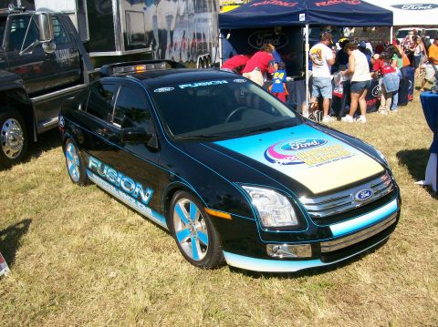 2003 Mercury Marauder - A black Ford Fusion is parked on grass with a Ford tent and people in the background.