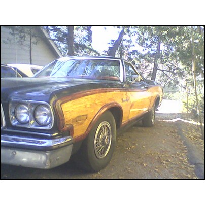 1973 Ford Ranchero - A vintage coupe utility vehicle with distinctive wood paneling is parked outdoors.