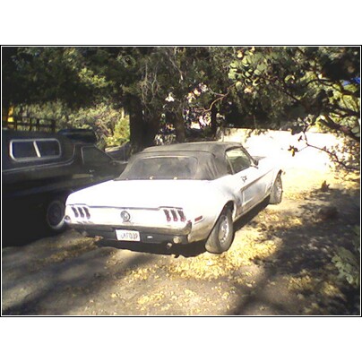 1968 Ford Mustang convertible parked outdoors, rear view. Another vehicle is partially visible to the left